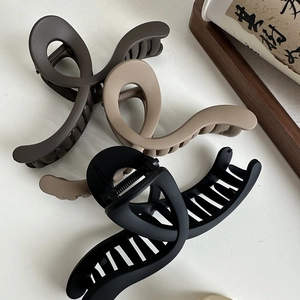 Three large matte wavy hair claws in brown and black on a clean white surface