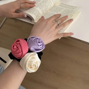 Close-up of elegant satin rose scrunchies in pink, purple, and cream for hair or wrist