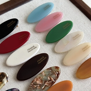 Macro detail of acetate oval hair clips featuring the gold France Handmade logo