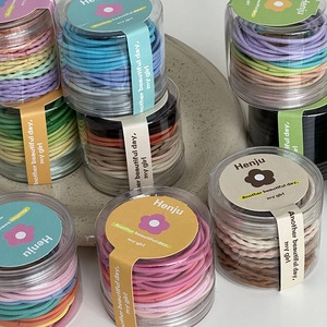 Detailed view of colorful high-elastic hair ties in transparent cylindrical jars for girls
