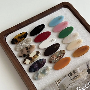 Detail of colorful acetate oval hair clips with FRANCE Handmade engraving in a wooden tray