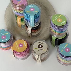 Close-up of assorted colorful elastic hair ties set in transparent cylinder packaging jars
