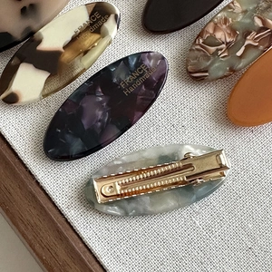 Oval acetate hair clips with marble patterns and gold metal duckbill clips