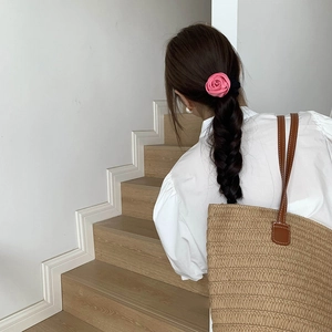 Detail of pink satin 3D rose flower scrunchie on a braided hairstyle for women