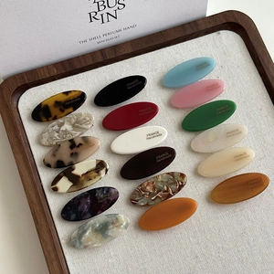 16-piece set of oval acetate hair clips in various solid colors and marble patterns