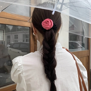 Detailed back view of a 3D pink satin rose hair scrunchie styled on dark hair