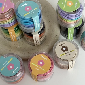 Detail of colorful elastic hair ties in a clear jar with a soft macaron color palette