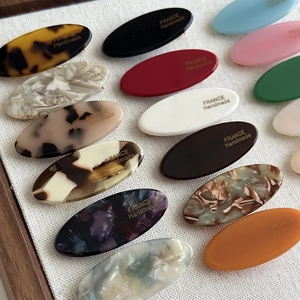 Detail of oval acetate hair clips with France Handmade gold foil lettering and marble textures