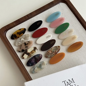 Variety of handmade oval acetate hair clips in tortoiseshell and marble patterns on a tray