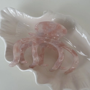Détail d'une pince à cheveux en acétate rose marbré avec lettrage fait main
