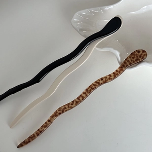 Close-up of wavy acetate hair sticks in black, cream, and tortoiseshell patterns