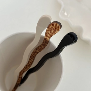 Close-up of minimalist wavy acetate hair pins in white, tortoiseshell, and black finish