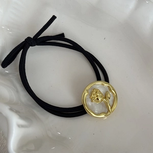 Detailed view of French vintage black hair tie with gold rose and mother of pearl inlay