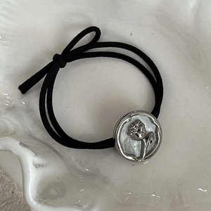 Detailed macro view of the alloy rose relief and pearl texture inlay on a black hair tie