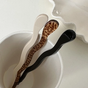 Close-up of wavy acetate hair pins in cream, leopard print and black on ceramic tray