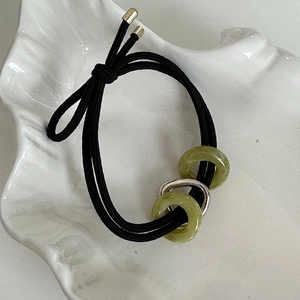 Détail d'un élastique à cheveux avec anneaux en jade vert et accent en métal argenté