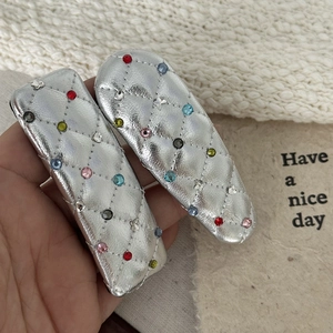 Close-up of silver leather hair clips with colorful rhinestones and quilted pattern