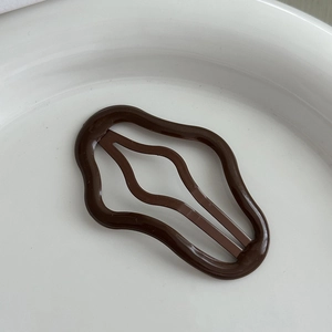 Macro di una clip per capelli ondulata marrone caffè su un piatto di ceramica bianca