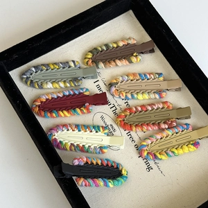 Detail of multi-colored hand-woven duckbill hair clips neatly arranged in a vintage tray