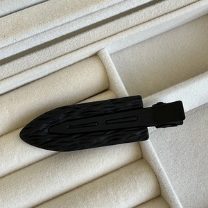 Dettaglio del fermaglio nero con trama a onde su espositore per gioielli in velluto