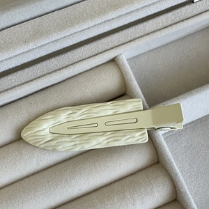 Dettaglio del fermaglio per capelli color crema con texture legno in un portagioie