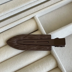 Dettaglio di fermaglio per capelli marrone scuro con trama legno in scatola di velluto