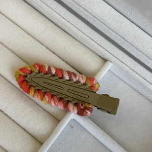 Close-up of colorful knitted yarn hair clips with wave texture on a soft white tray