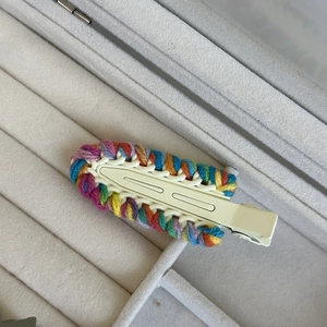 Detail of multi-color woven wool hairpin with off-white metal clip and handmade texture