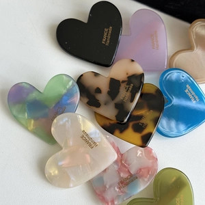 Close-up of heart-shaped acrylic hair clips in various tortoise and solid colors