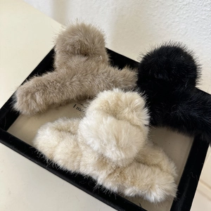 Detail of plush faux fur hair claws in black, khaki, and cream on a display tray