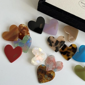 Detailed view of heart-shaped acrylic hair clips with leopard print and marble textures