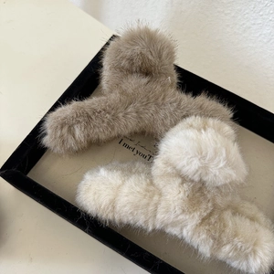 Macro view of plush faux fur hair claw clips in beige and brown colors for autumn