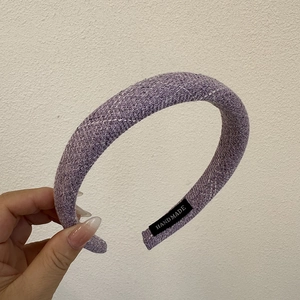 Close-up of lavender striped fabric headband featuring a woven texture and hand made label