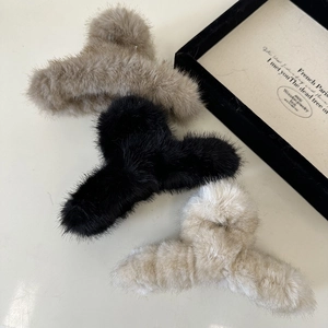 Detailed view of large plush faux fur hair claws in beige, black and cream white colors