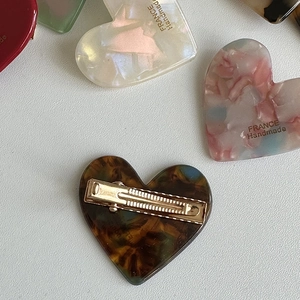 Macro detail of heart-shaped acetate hair clips with vibrant leopard patterns