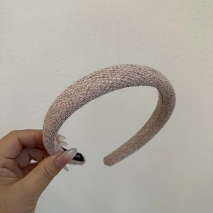 Detailed texture of thick pink tweed headband showing woven fabric and wide padded design