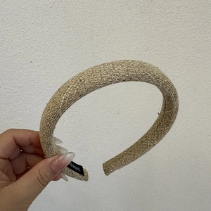 Close-up of handmade khaki tweed sponge headband with textured weave and black woven label