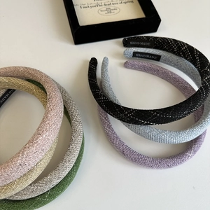 Detail of handmade padded headbands in various colors on a minimalist white display