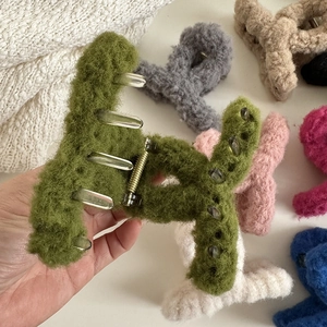 Close-up of grass green plush faux fur hair claw clip with multiple colors in background