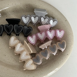 Close-up of assorted heart-shaped hair claws in pastel colors on a ceramic tray
