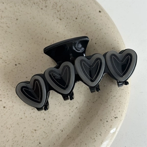 Close-up of a double-layered heart claw clip with a glossy black and grey finish