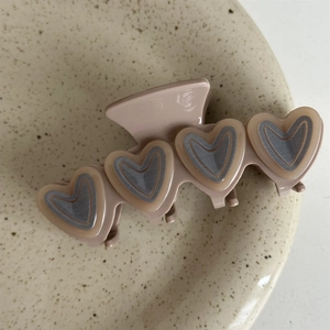 Detail of dusty pink double-layered heart hair claw clip on a ceramic tray