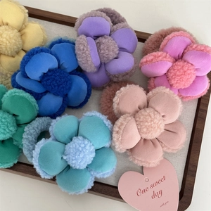 Gros plan d'élastiques à cheveux fleurs en peluche colorées sur un plateau en tissu