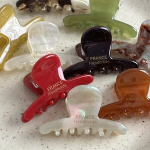 Pinces à cheveux en acétate fait main couleurs variées sur un plateau en céramique