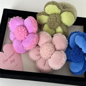 Détail d'élastiques à cheveux en peluche avec fleurs violettes, vertes, roses et bleues