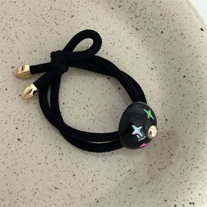 Detail of double-strand elastic hair tie with colorful star pattern and gold metal ends