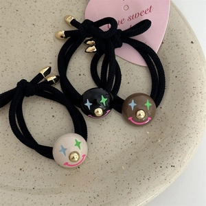 Detailed shot of three colorful elastic hair ties with star-eyed smiley face beads