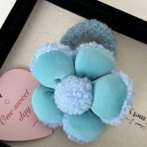 Détail d'un chouchou fleur en velours bleu et tissu laineux doux pour accessoires cheveux