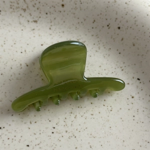 Gros plan d'une pince à cheveux en acétate vert olive avec gravure dorée France Handmade