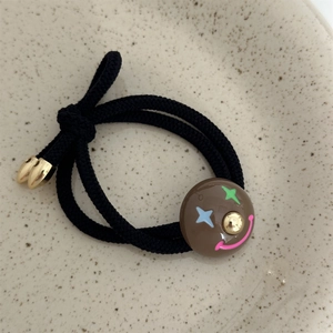 Close-up of black braided hair tie featuring a brown clown pendant with star eyes